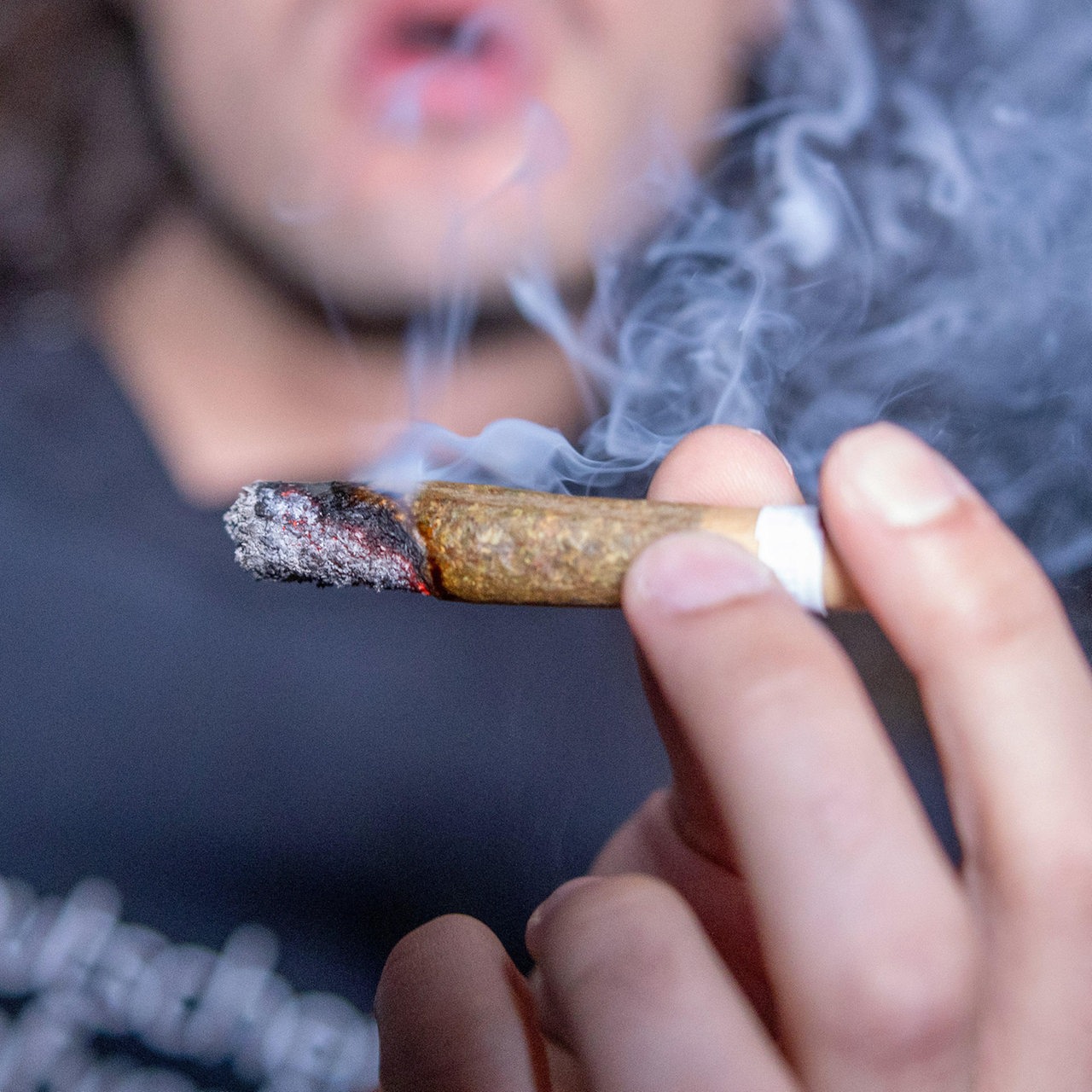 Ein junger Mann raucht einen Joint (Symbolfoto)