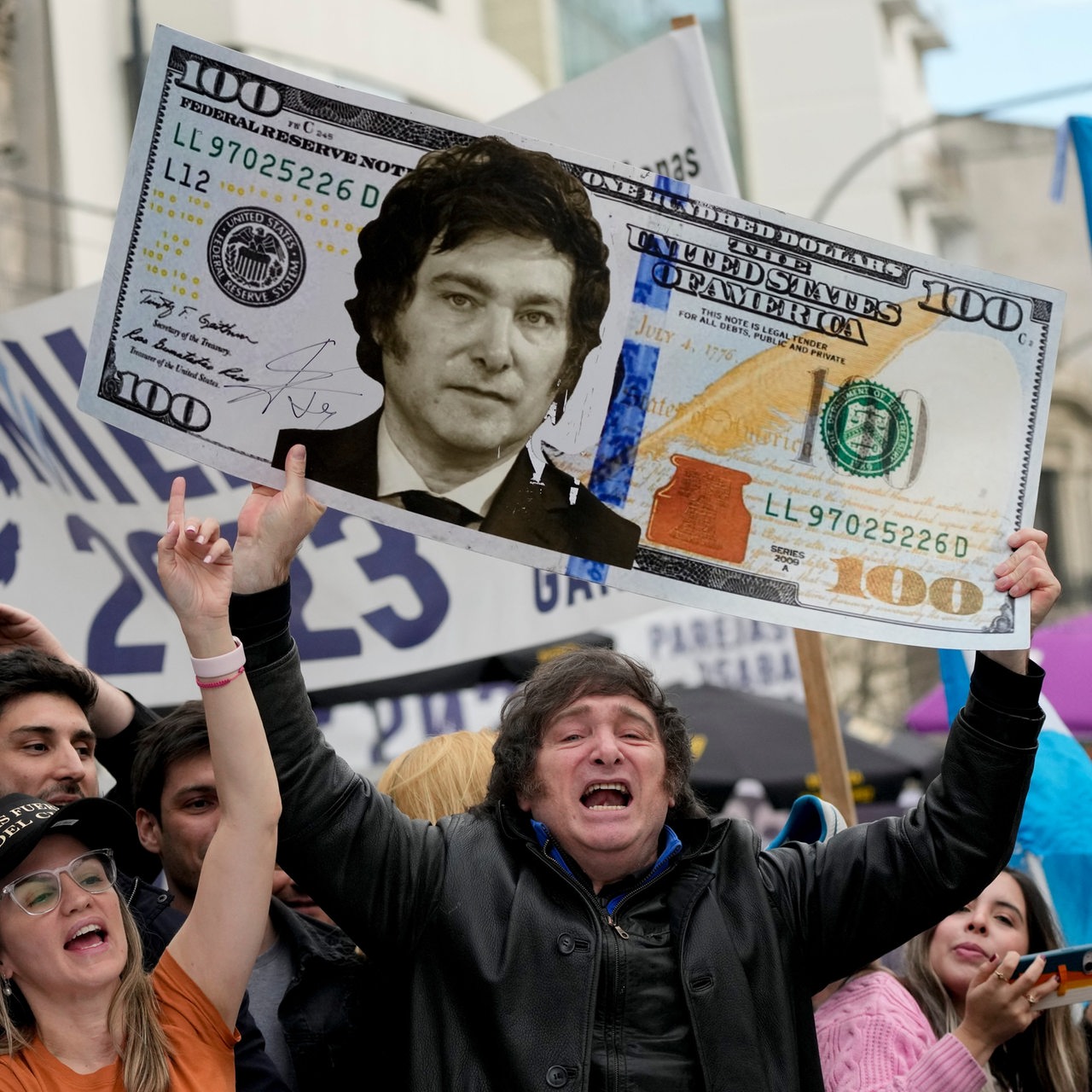 Der Argentinische Politiker Javier Milei hält eine übergroße Dollarnote mit seinem Konterfei in einer Menge in die Höhe.