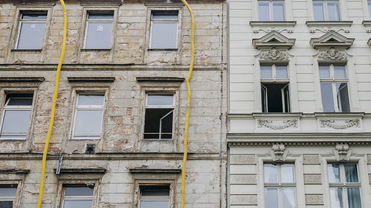 Ein sanierungsbedürftiges Wohnhaus steht neben einem bereits renovierten Haus. (Symbolbild)