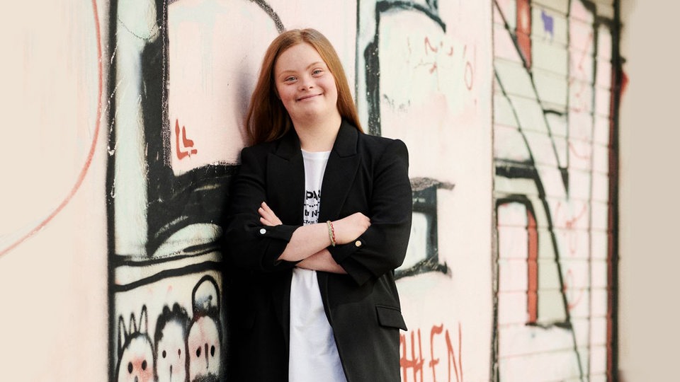 Amelie Gerdes steht vor einer mit Graffity bemalten Wand