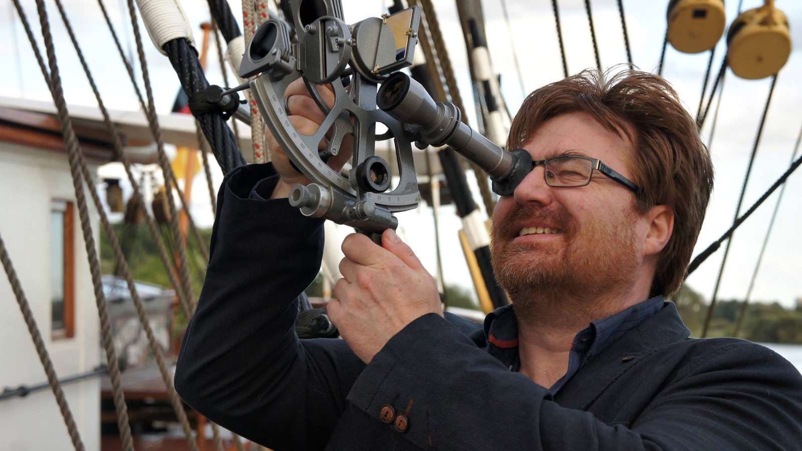Ein Mann schaut durch ein modernes Teleskop auf einem Schiff