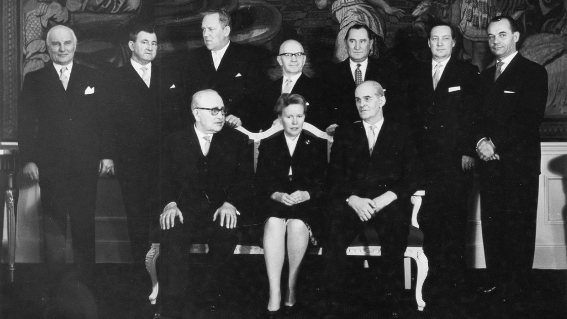 Annemarie Mevissen sitzt auf einer Bank, hinter und neben ihr die anderen Senatsmitglieder. 