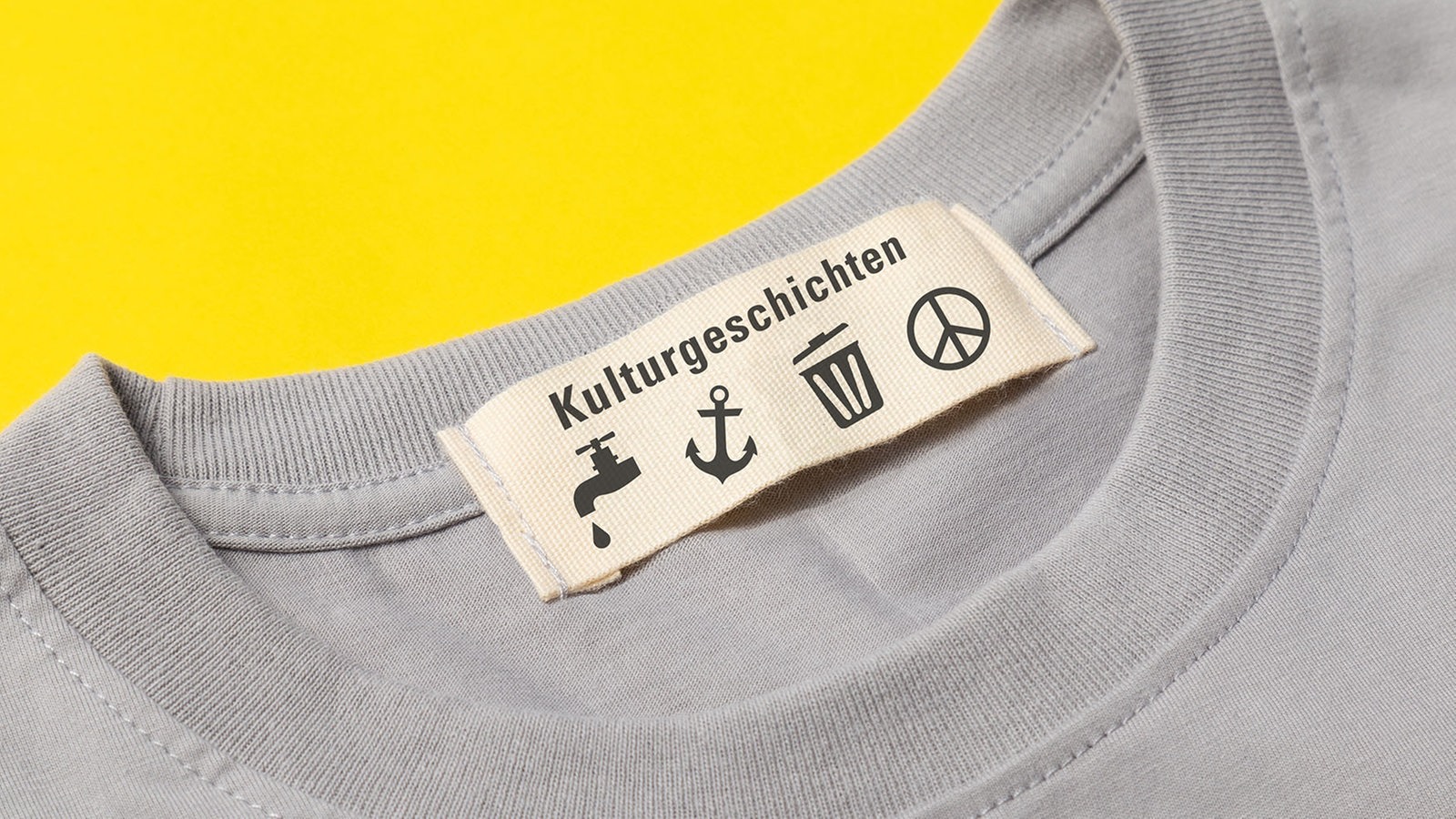 Ein Baumwoll-T-Shirt mit einem Etikett, auf dem das Wort "Kulturgeschichtne" und mehrere Zeichen abgebildet sind (Symbobild)