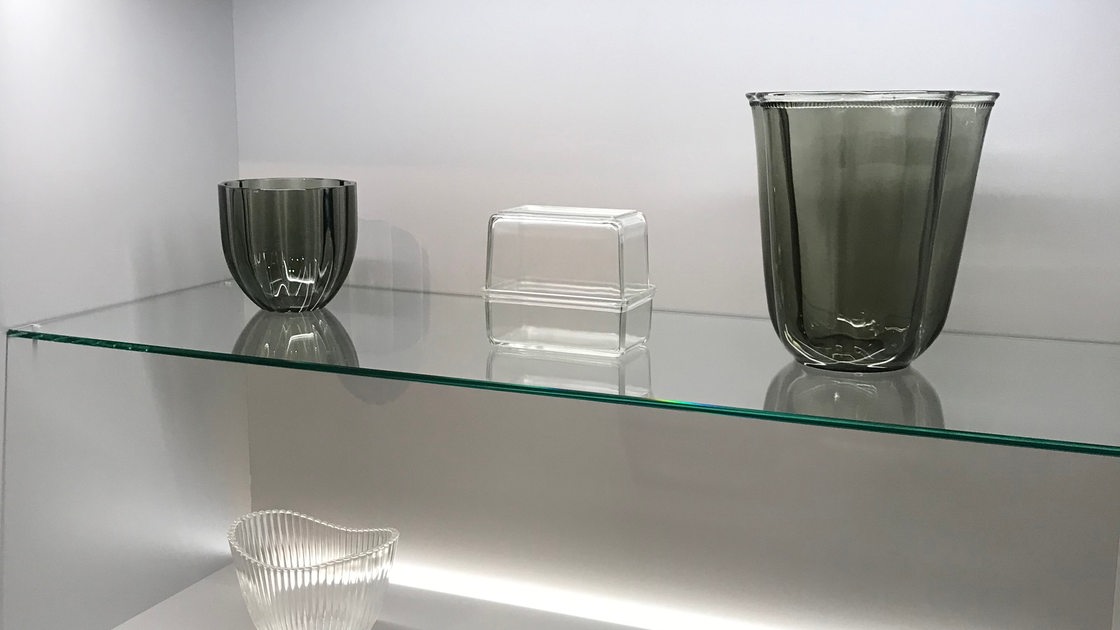 Verschiedene Vasen und Schalen aus Glas stehen in einer Ausstellungsvitrine.