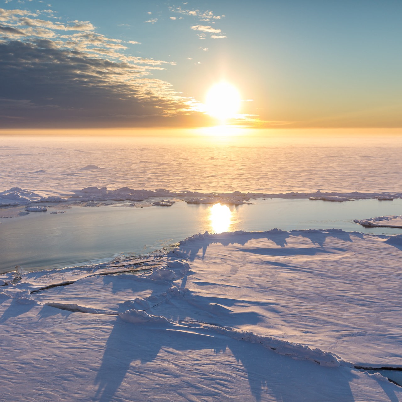 Blick in die Arktis während die tiefhängende Sonne am Horizont zu sehen ist.