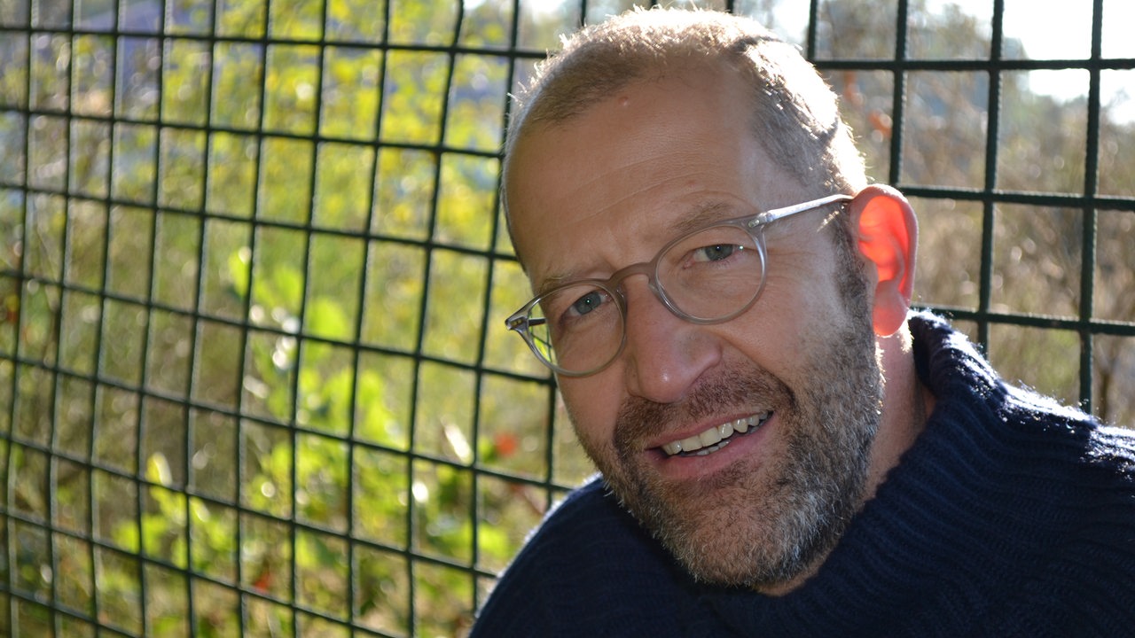 Ein Mann mit Bart und Brille lächelt in die Kamera