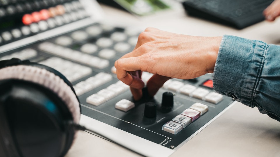 Eine Hand dreht einen Knopf in einem Radio-Studio