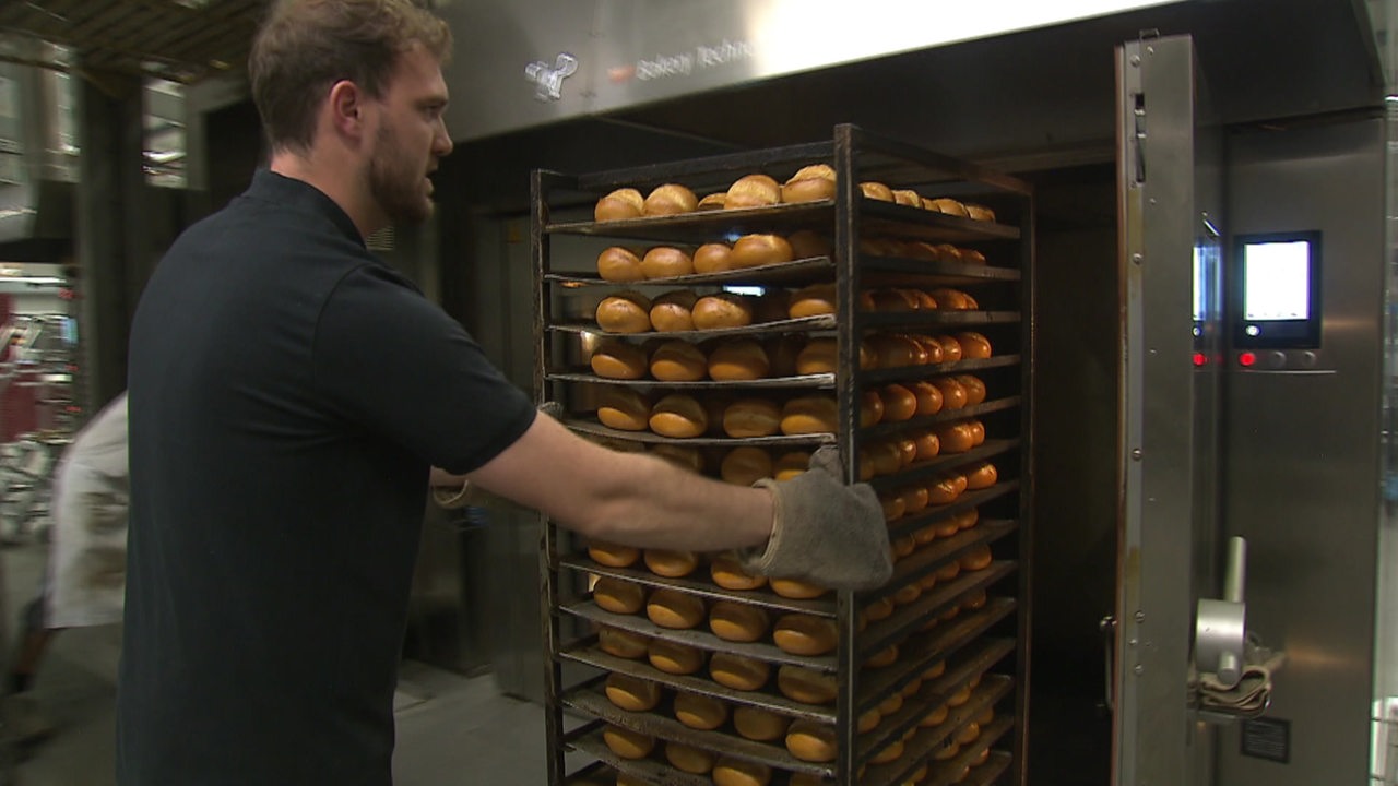 Ein Mitarbeiter der Wümmer Bäckerei Sammann holt einen Wagen voller Brötchen aus dem Ofen.