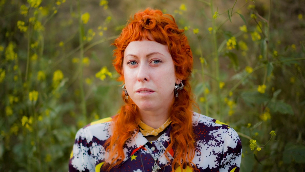 Porträt von Shannon Lay mit roten Haaren vor grüner Wiese
