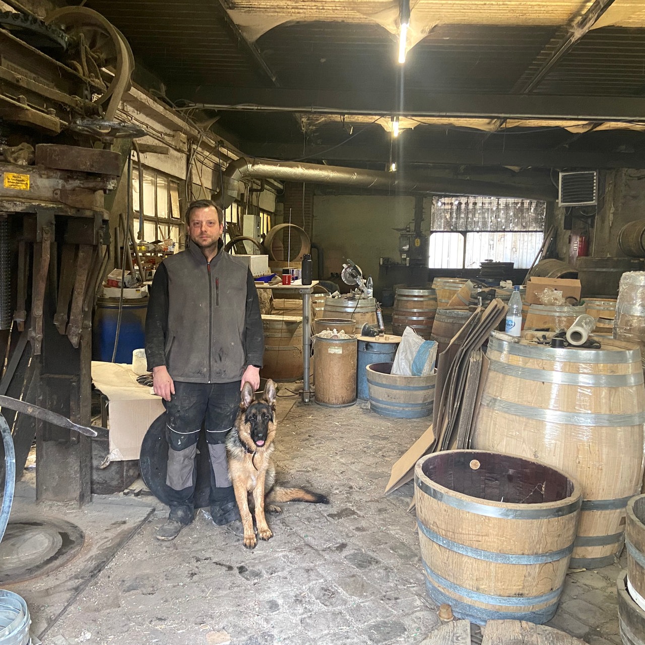 ein Mann steht mit seinem Hund in einer alten Werkstatt