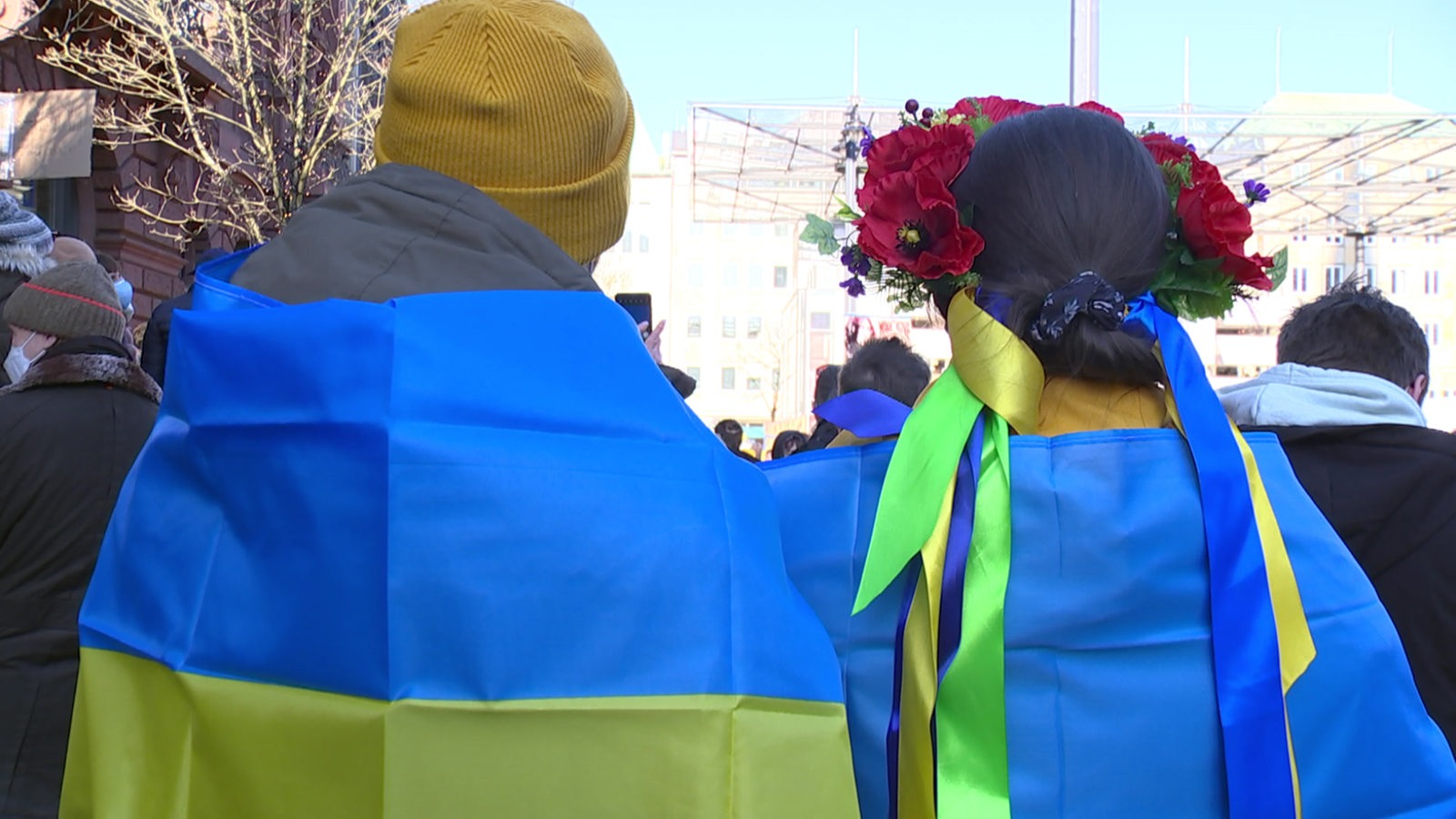Zwei Menschen stehen mit dem Rücken zur Kamera in der Bremer Innenstadt und tragen die ukrainische Flagge.