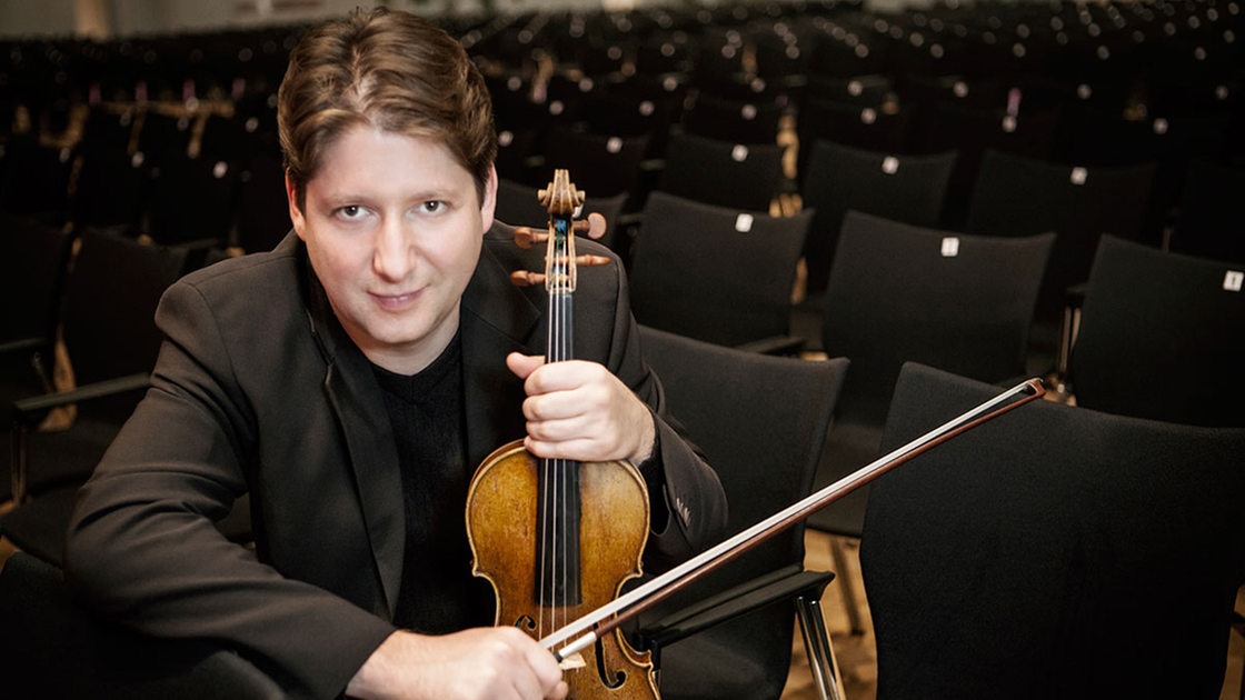 Porträt des Violinisten Denis Goldfeld im Theatersaal mit Geige
