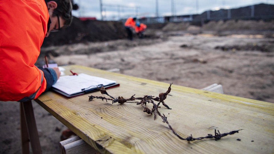 Ein Mann schreibt an einem Tisch, der sich an einer Baustelle befindet.