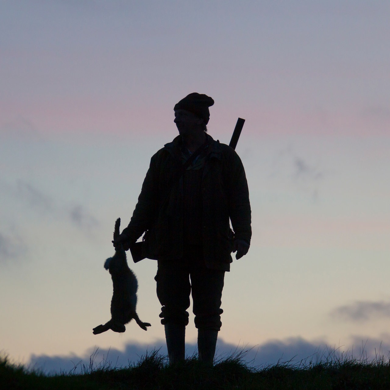 Silhouette eines Jägers mit einem Hasen