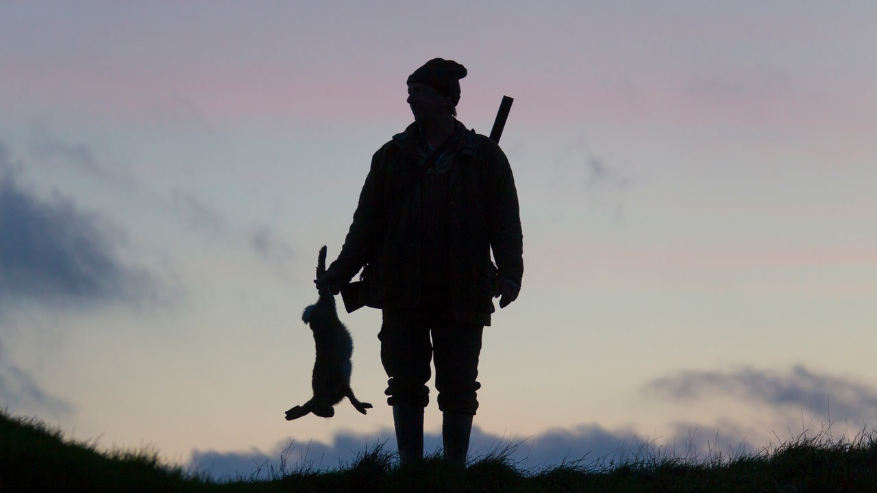 Silhouette eines Jägers mit einem Hasen