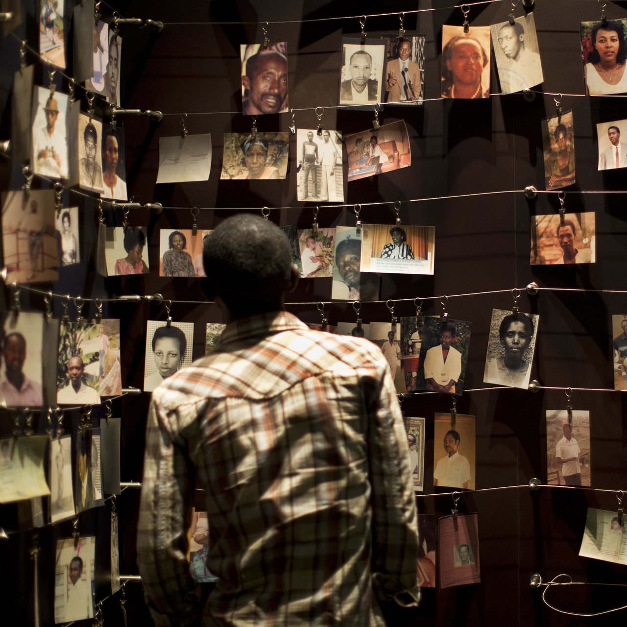 Ein Besucher schaut sich Bilder von Menschen an, die im Kigali Genocide Memorial Centre ausgestellt sind.