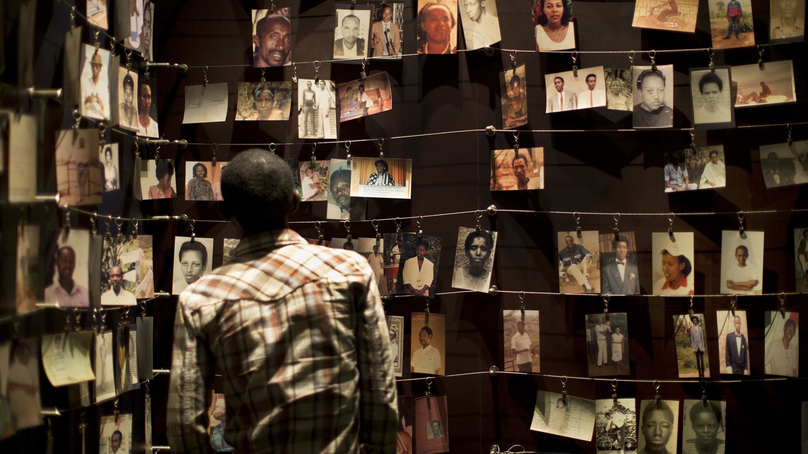 Ein Besucher schaut sich Bilder von Menschen an, die im Kigali Genocide Memorial Centre ausgestellt sind.