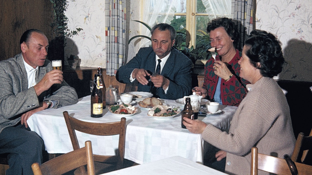 Sechziger Jahre, Menschen, Essen und Trinken, zwei Maenner und zwei Frauen sitzen am Tisch in einer Gaststaette