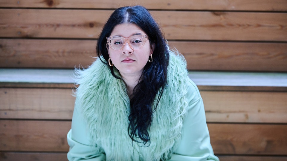 Yasmine M'Barek, Journalistin und Autorin, sitzt auf Stufen in Berlin