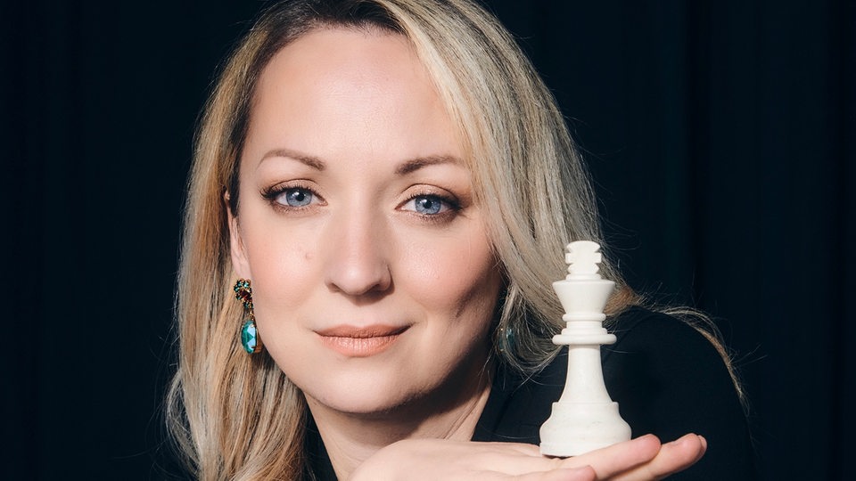 Ein Porträt von Elisabeth Pähtz mit einer Schach-Figur in der Hand.
