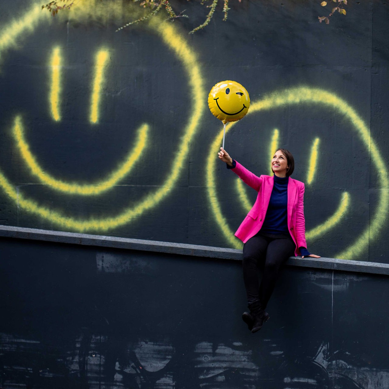 Eine Frau hält einen Smiley-Ballon in der Hand