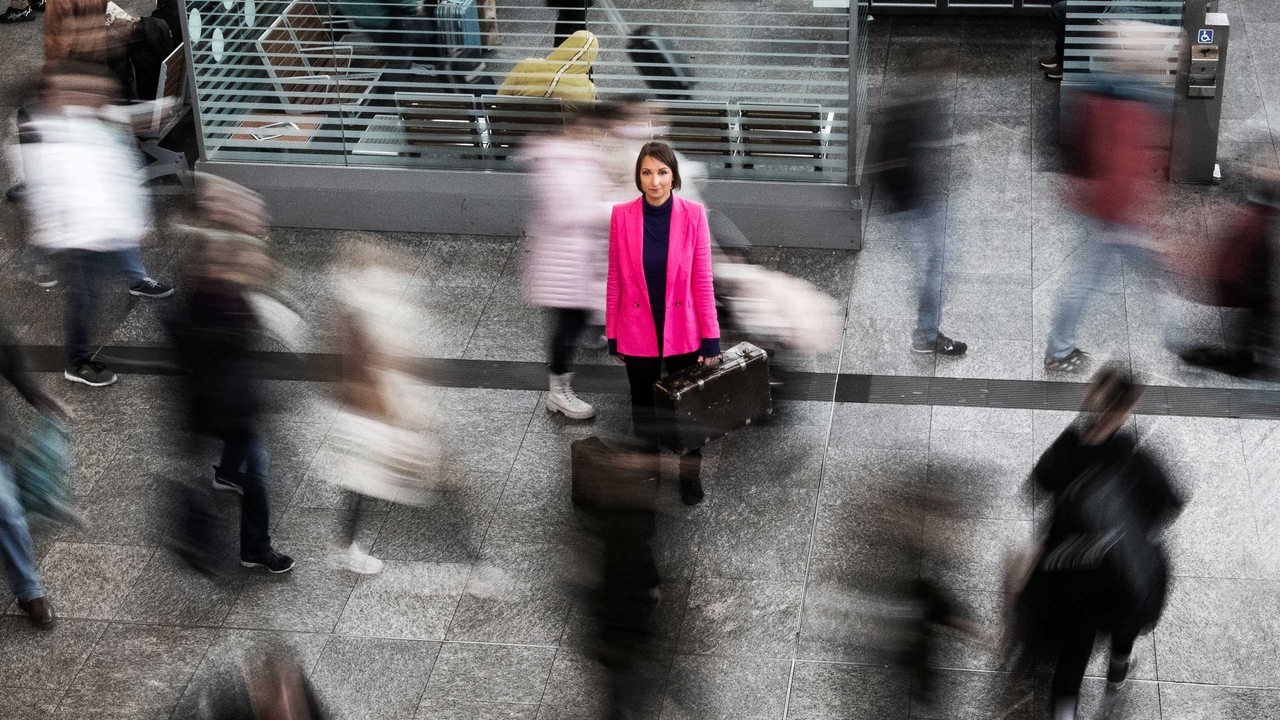 Eine Frau mit Koffer im Bahnhof inmitten von Menschen