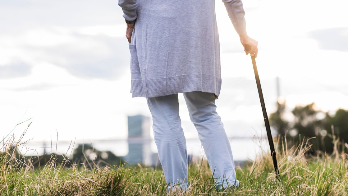 Eine Frau mit einem Gehtstock auf einem Feld (Symbolfoto)