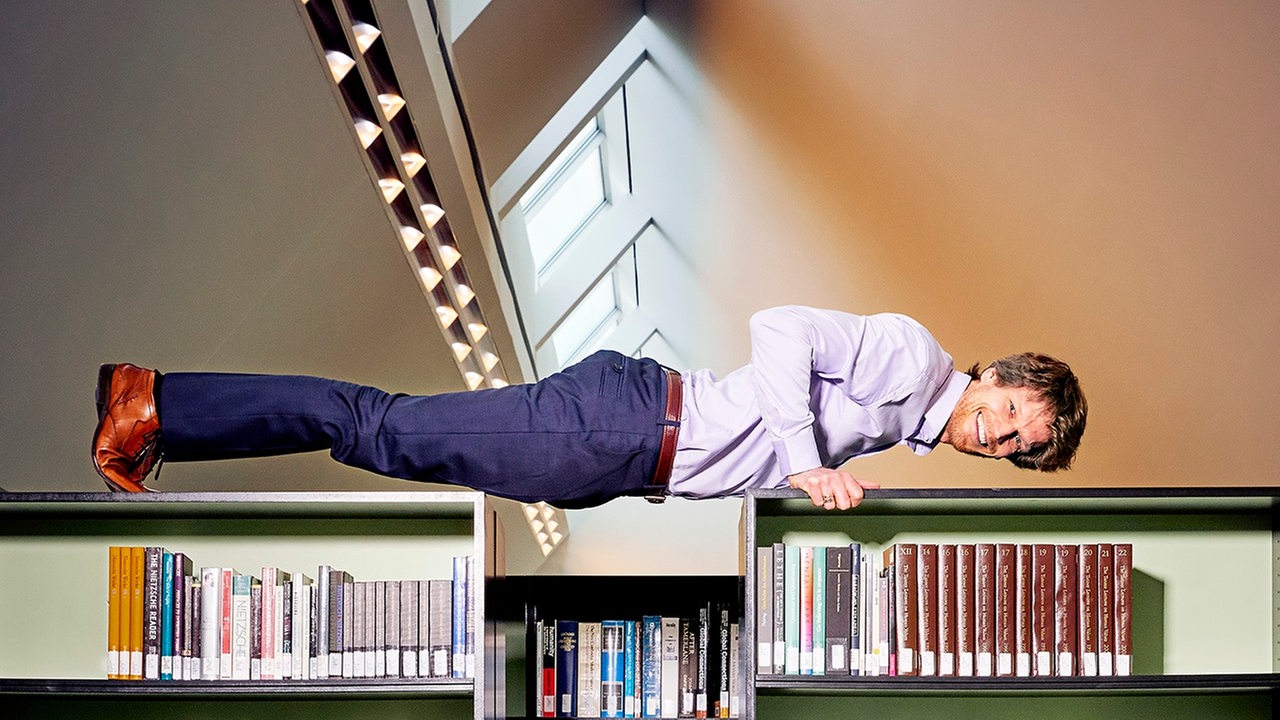 Sven Völpel macht einen Liegestütz über Bücherregalen