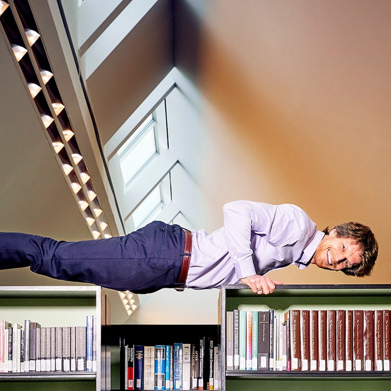 Sven Völpel macht einen Liegestütz über Bücherregalen
