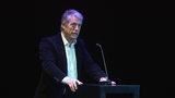 Schauspieler Hugh Grant steht in einem dunklen Anzug auf der Bühne beim Bremer Filmfest und hält eine Rede.