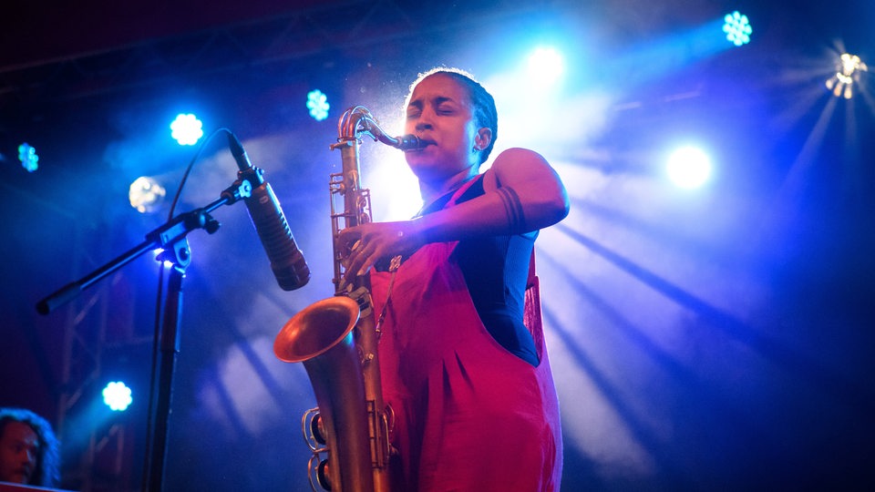 Eine Frau spielt Saxophone auf einer Bühne.