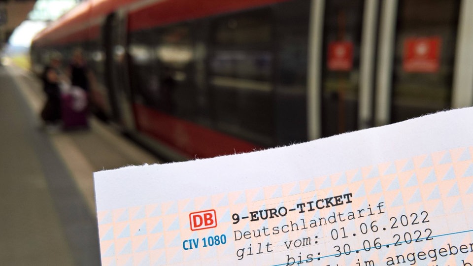 Ein Neun-Euro-Ticket, im Hintergrund ein Zug