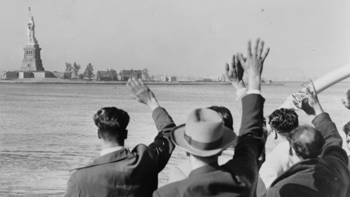 Ankommende Immigraten auf einem Schiff winken in Richtung Ellis Island (Archivbild)