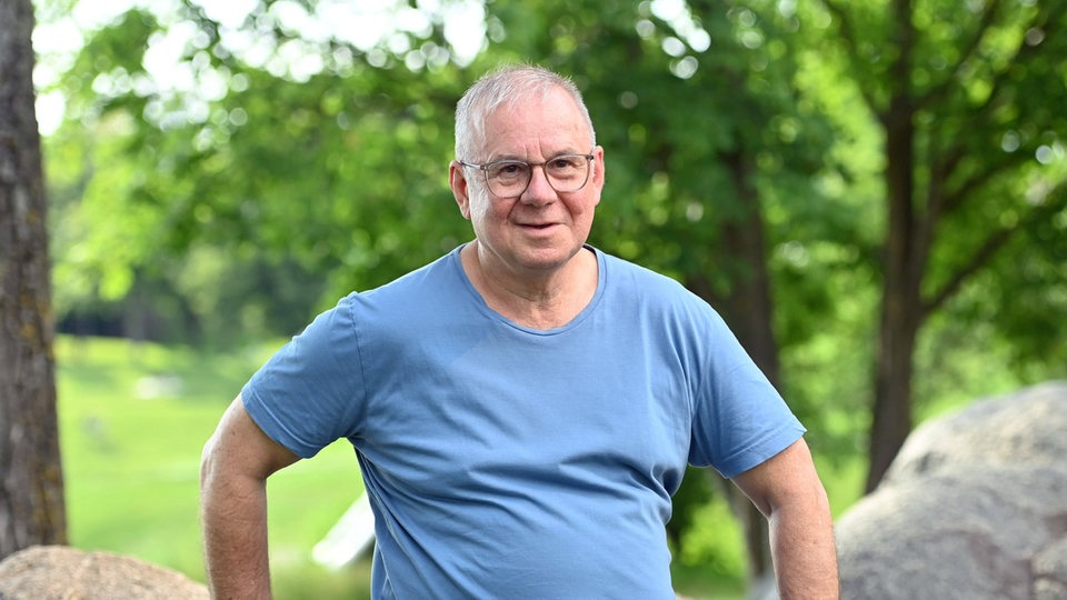 Joachim Krol sitzt auf Findlingen im Grünen