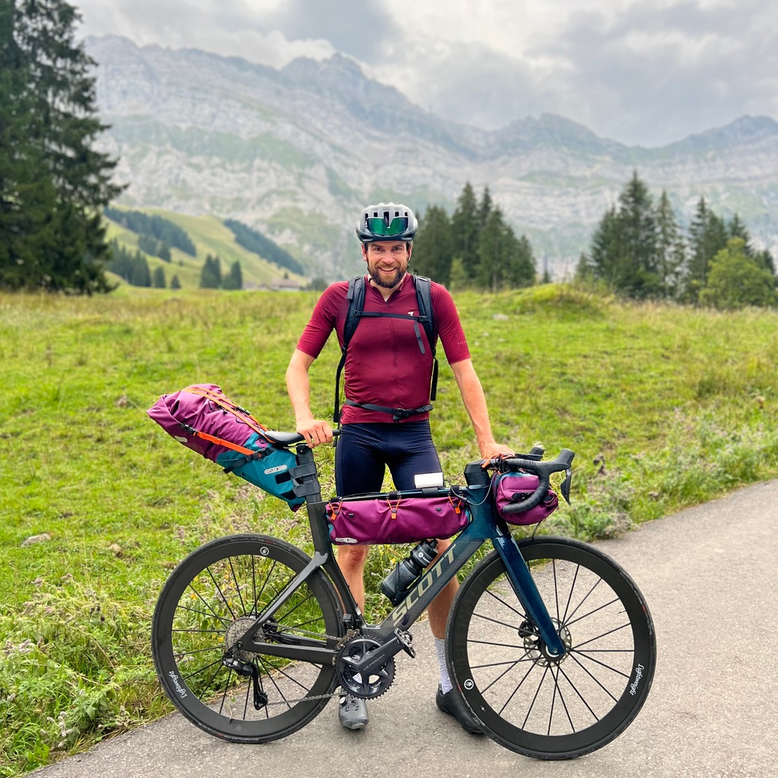 Jonas Deichmann mit seinem Rad vor einem Bergpanorama