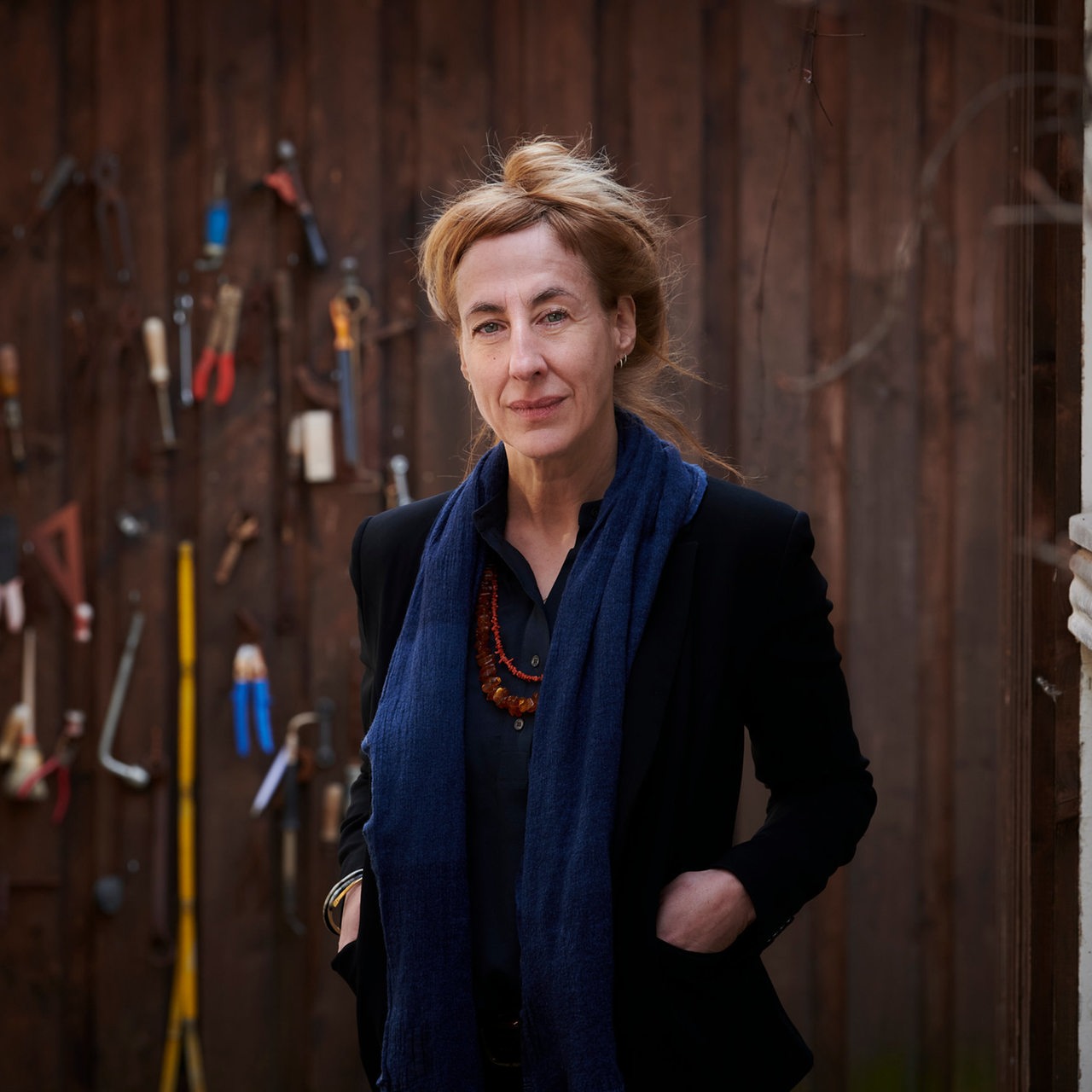 Die Autorin Judith Hermann steht vor einer Bretterwand mit Werkzeug