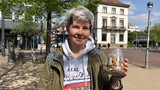eine Frau hält ein Glas mit Zigarettenkippen