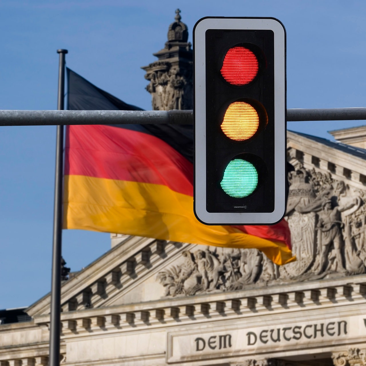 Themenbild Ampelkoalition, zwei Ampeln zeigen alle Fahnen vor dem deutschen Reichstagsgebäude