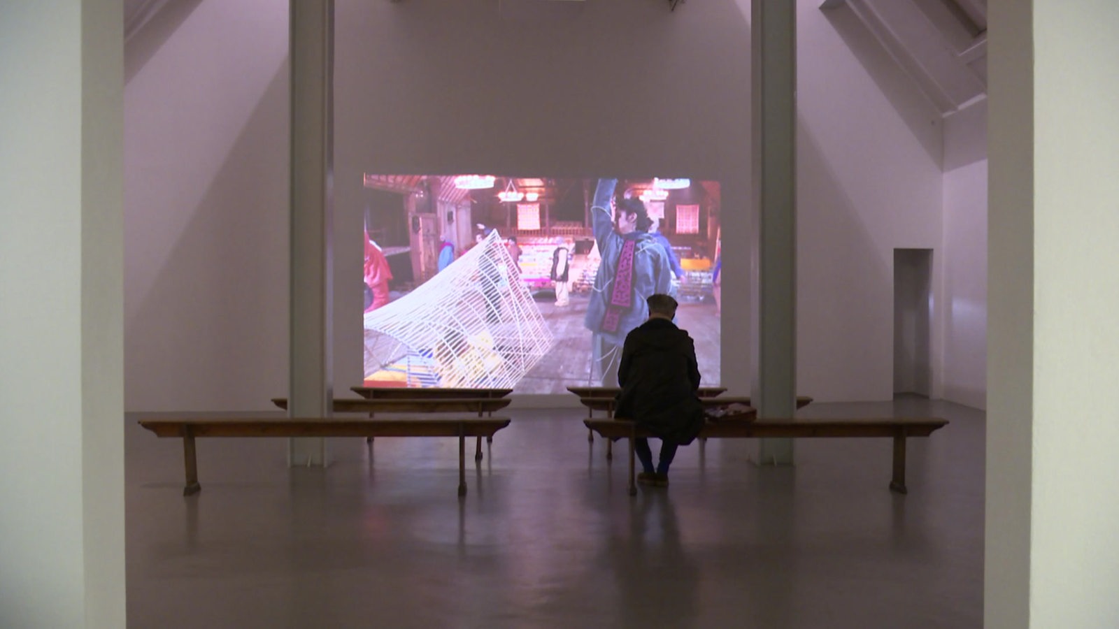 Die neue Ausstellung in der Weserburg zeigt Kunstinstallationen. Bänke sind vor einer Leinwand aufgestellt, auf der ein Film zu sehen ist.