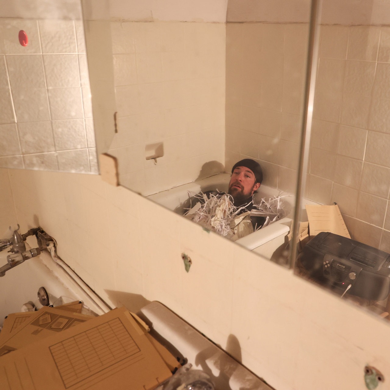 Christian Freund liegt in einer Badewanne mit Papierschnipsel