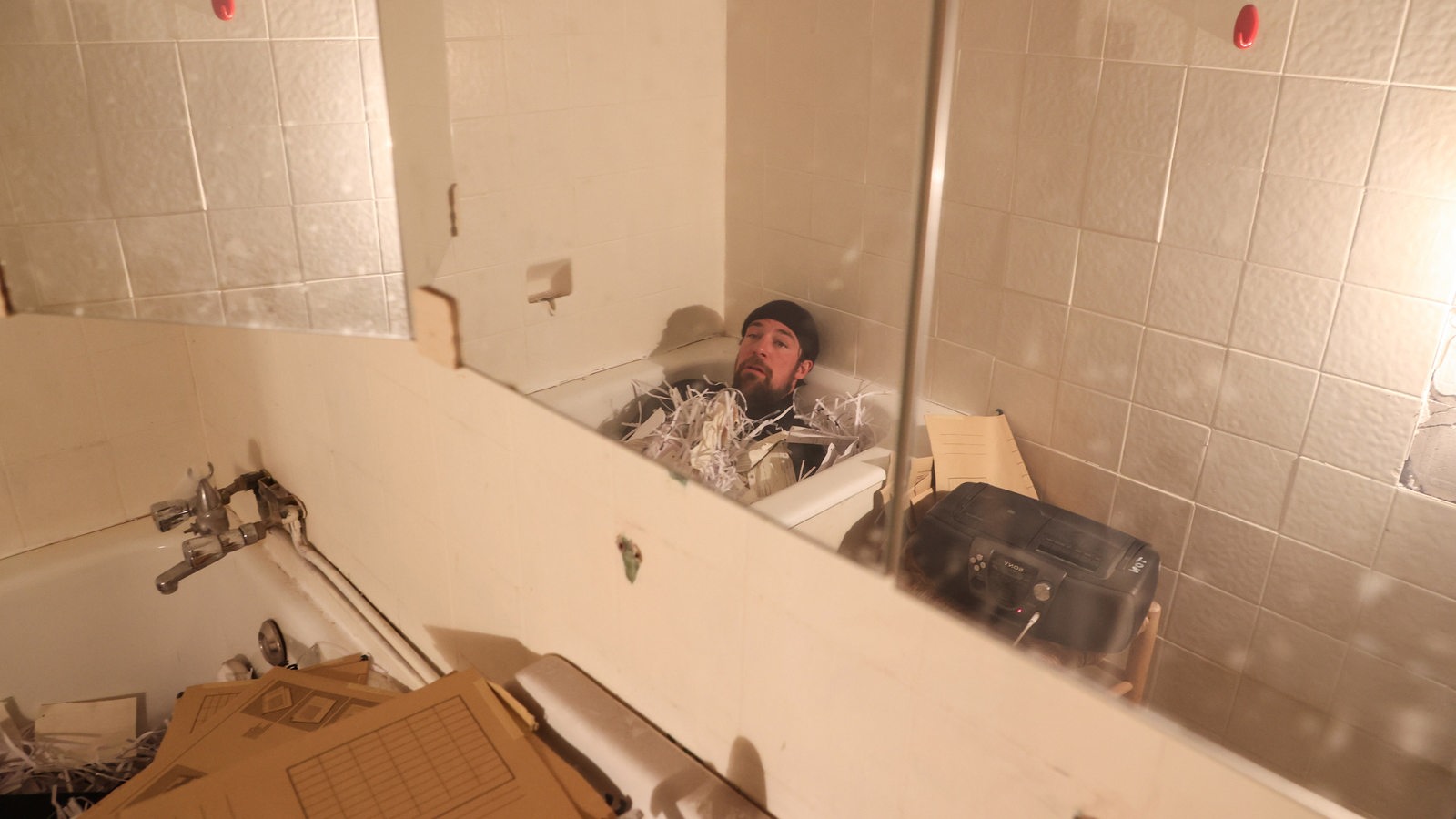 Christian Freund liegt in einer Badewanne mit Papierschnipsel