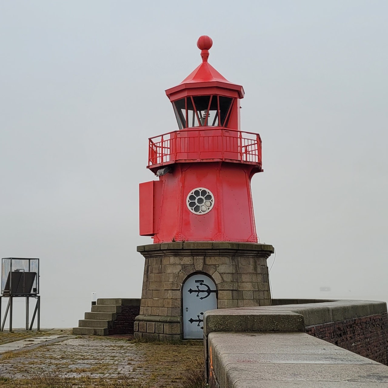 Ein kleiner roter Leuchtturm nah am Wasser