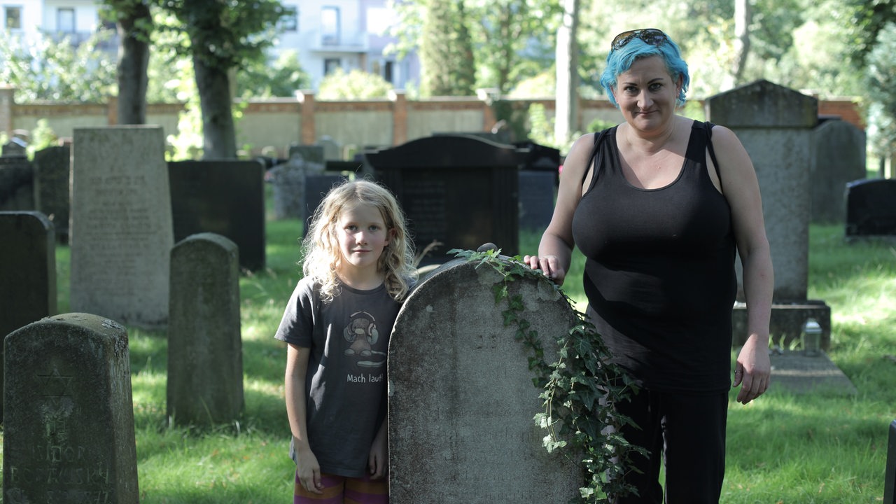 Eine Frau steht mit ihrer Tochter an einem Grab auf dem jüdischen Friedhof in Hastedt