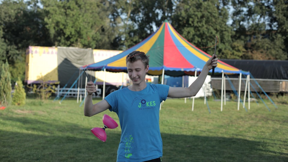 Blonder Junge führt etwas mit einem pinken Diabolo vor