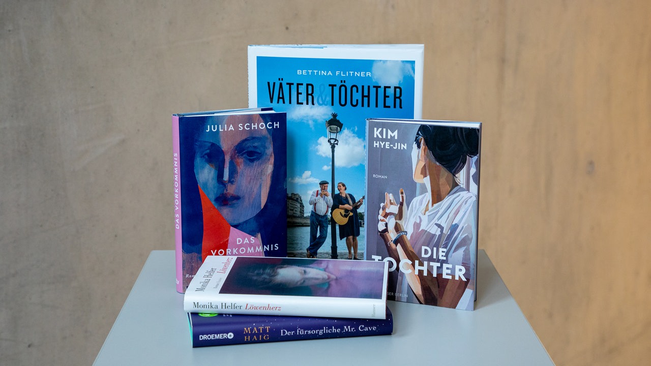 Bunte Bücher stehen und liegen auf einem weißen Tisch