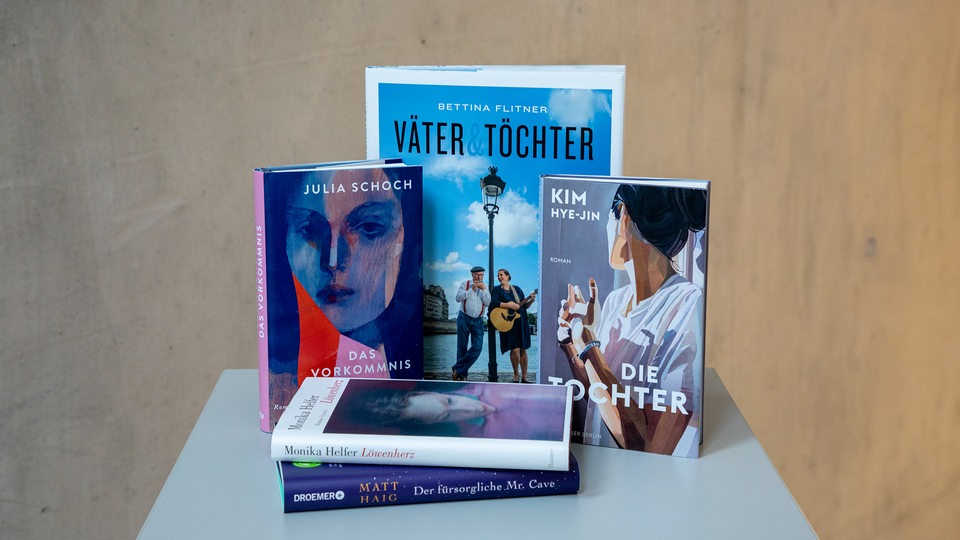 Bunte Bücher stehen und liegen auf einem weißen Tisch