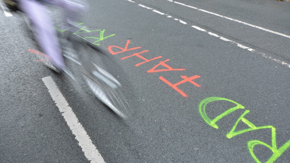 Fahrradfahrer saust über Schriftzug "Rad Fahr Rad"