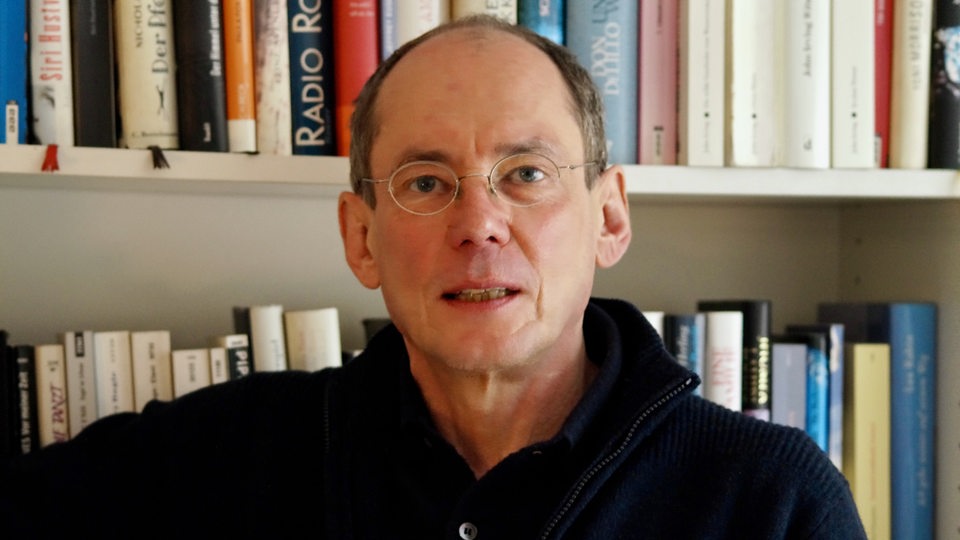 Der Krimiautor Max Bronski vor einem Bücherregal