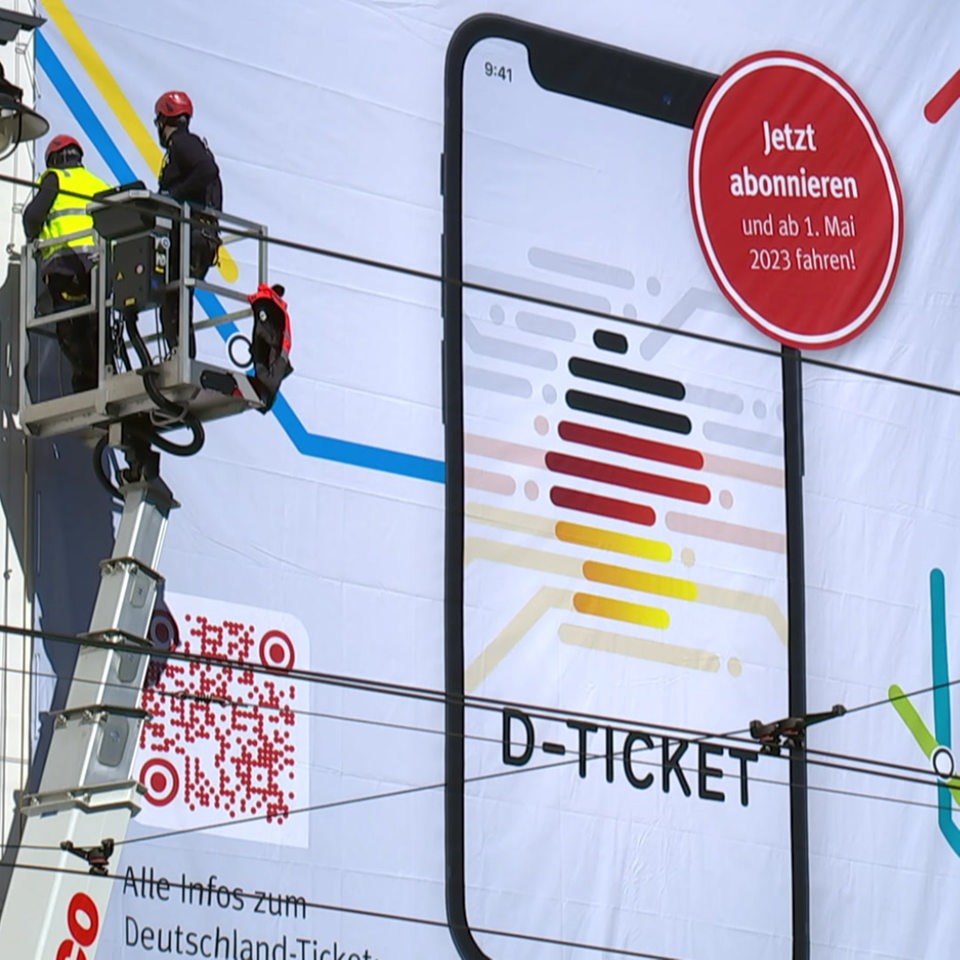 Ein großes Banner des Deutschland Tickets wird an der Bremer Domsheide an der Außenfassade eines Gebäudes angebracht.