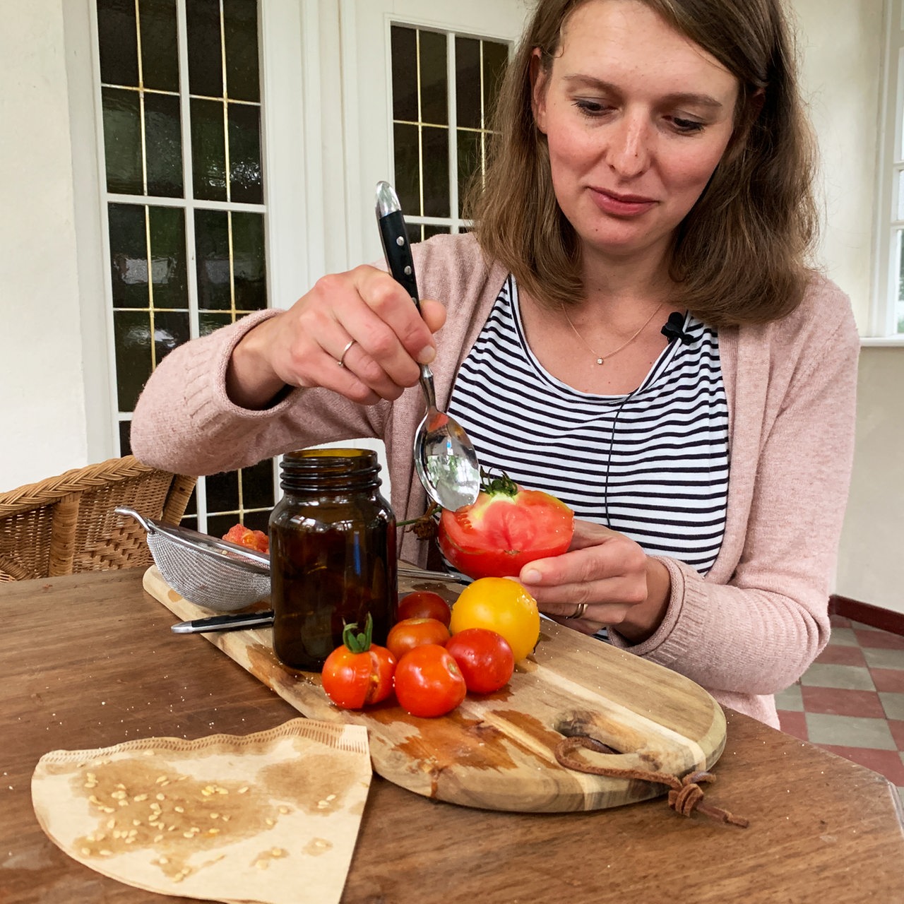 Eine Frau löffelt Samen aus einer Tomate
